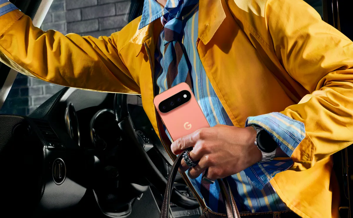 A person wearing a bright yellow jacket steps out of a car while holding a Google Pixel phone.